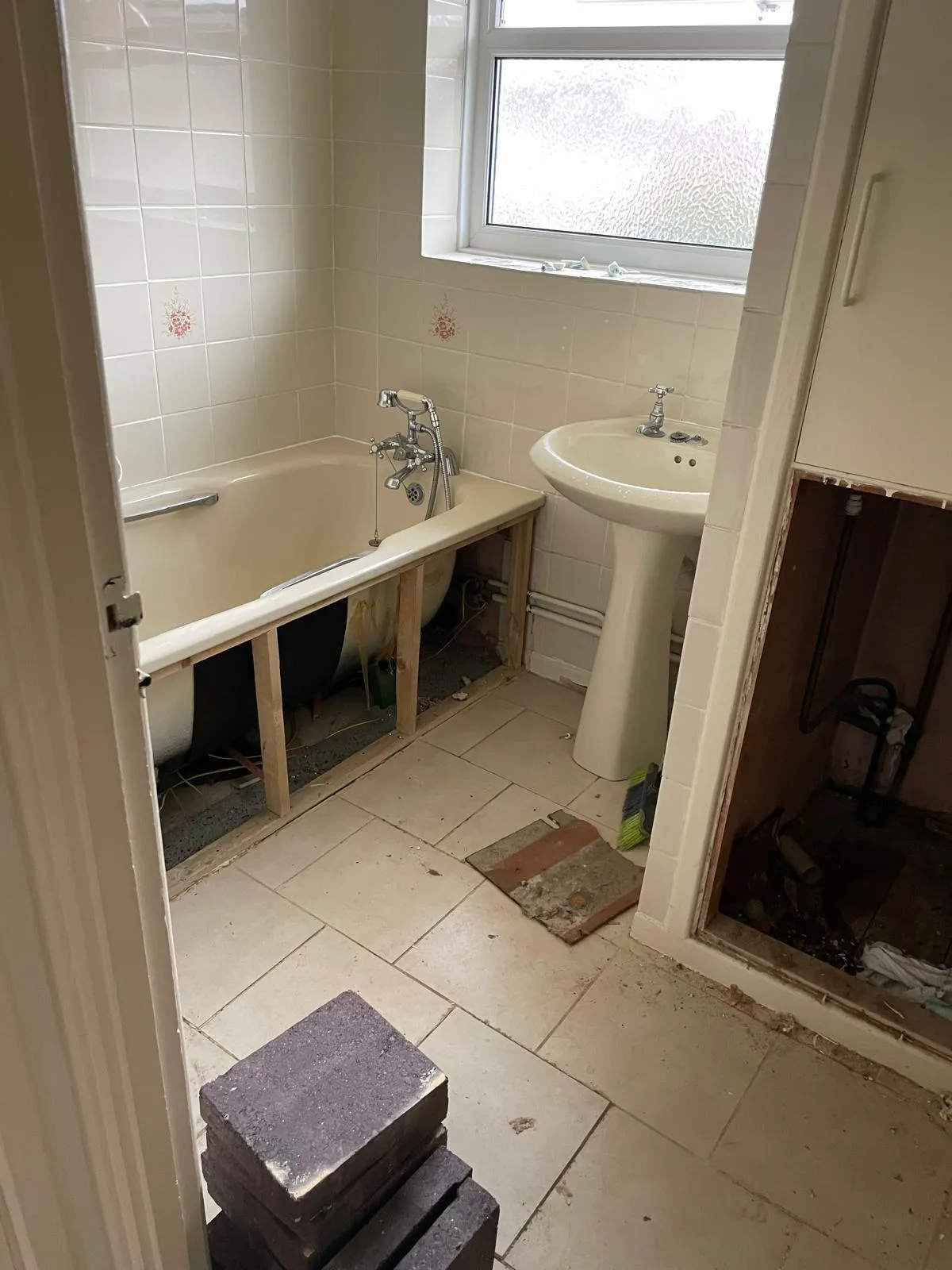 Tired bathroom with dated tiles and bath panel removed awaiting refit