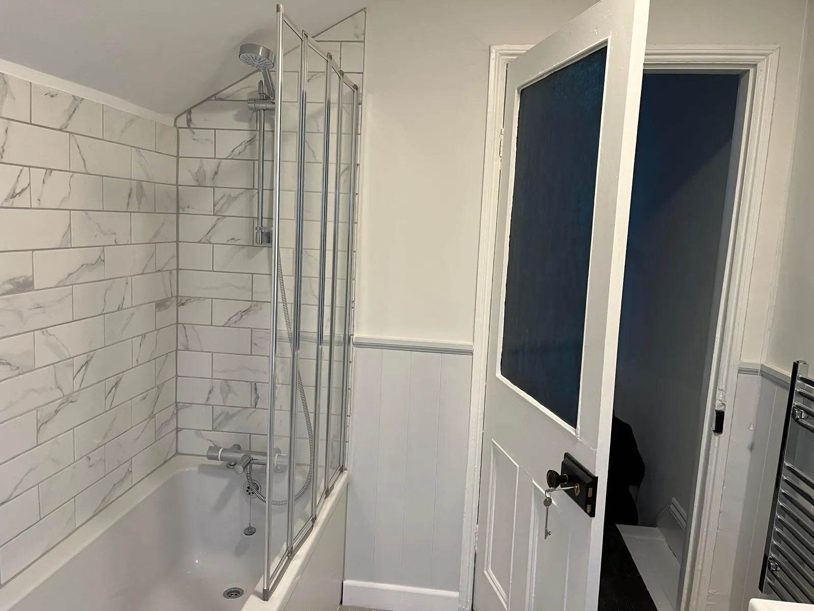 Finished bathroom with white metro tiles & shower over bath