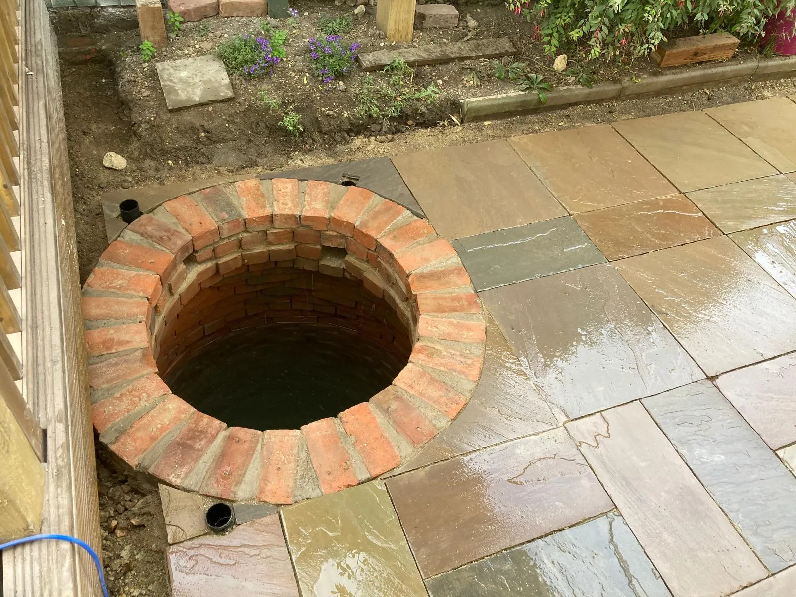 Newly laid Indian sandstone patio built around old brick well