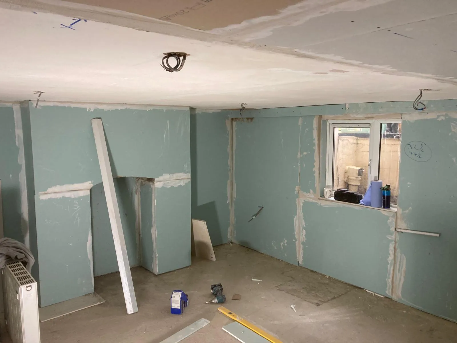 Worker applying waterproof tanking slurry to basement wall