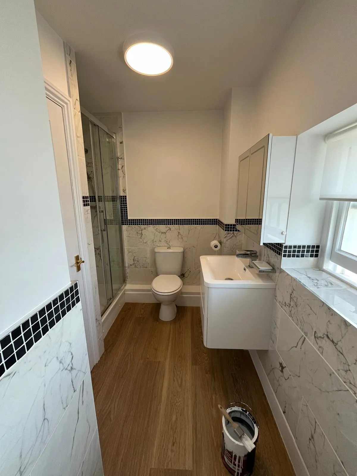 Completed bathroom with grey tiled walls, bath, vanity and shower
