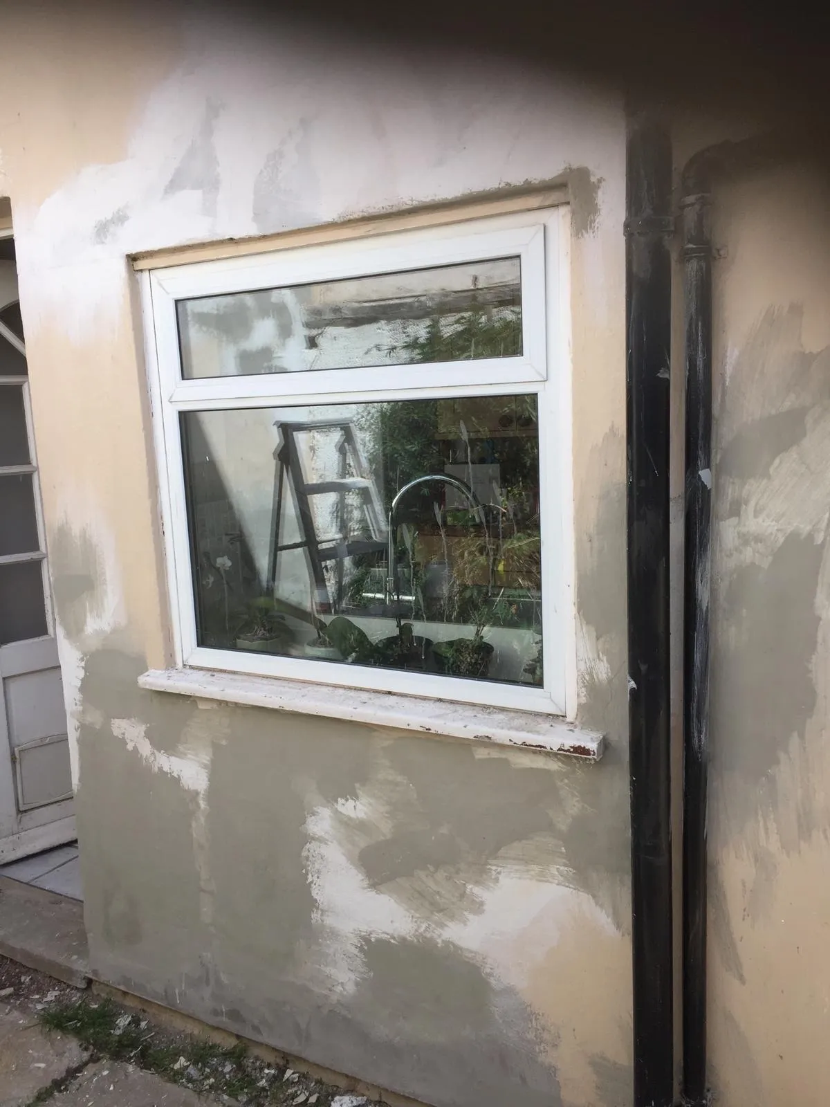 Exterior rendering repair around uPVC window, patchy render mid-application