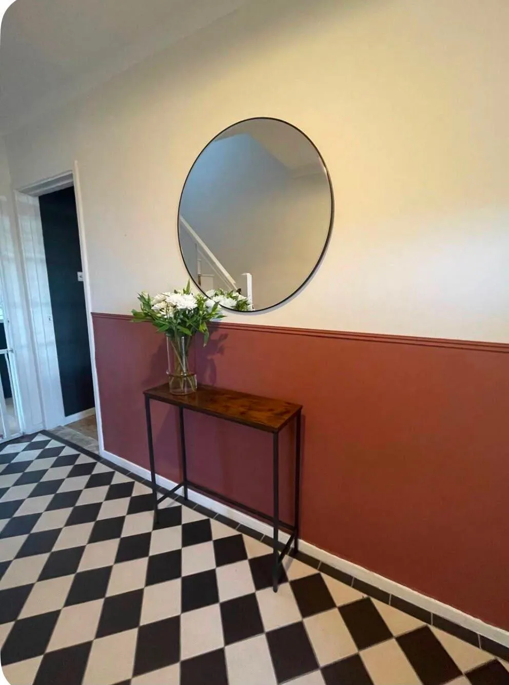 Entranceway finished with black-and-white checkered tiling and fresh decoration