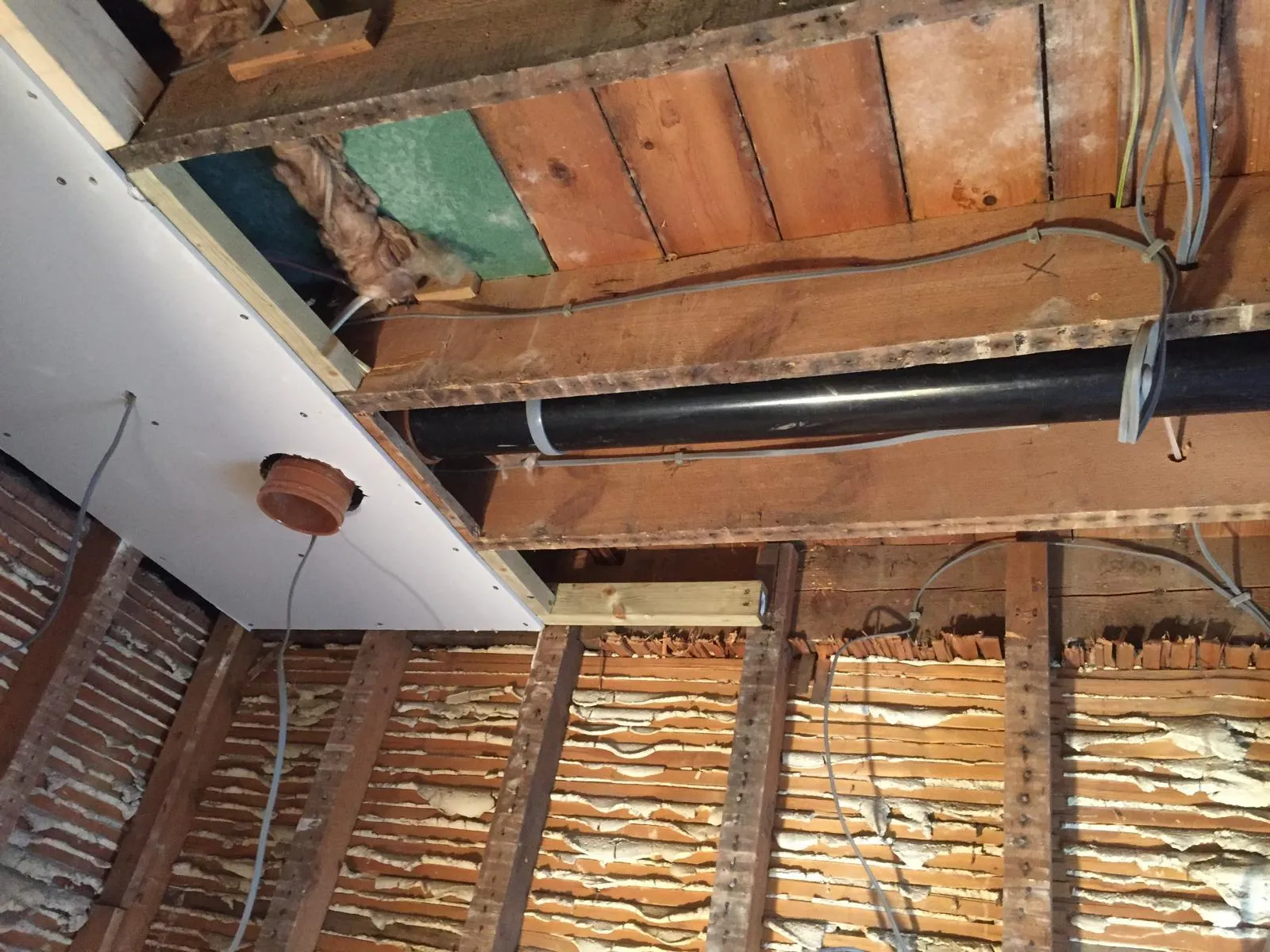 Stripped bathroom with tiles half removed and exposed pipework