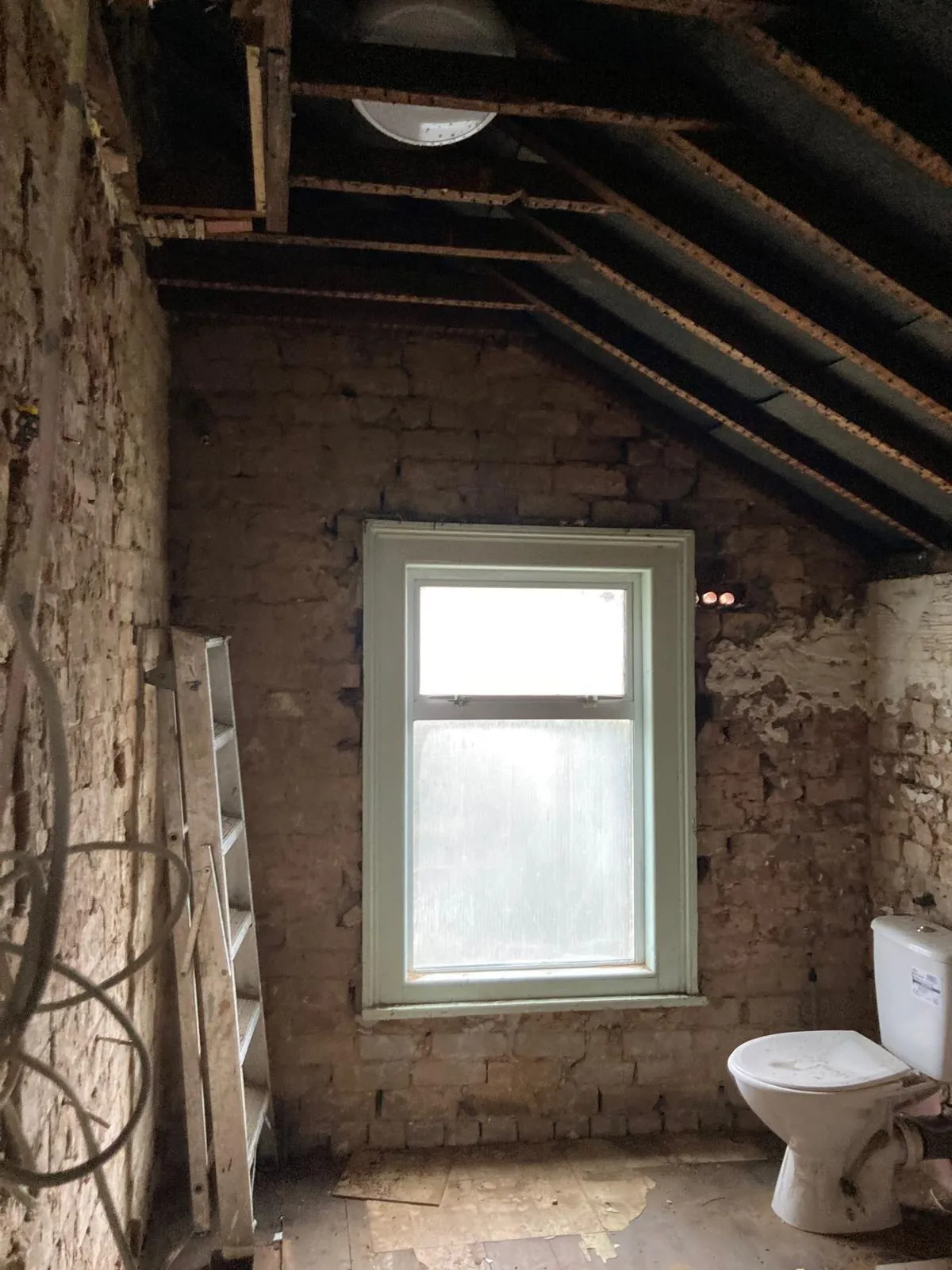 Old bathroom stripped back to brickwork and ceiling studs