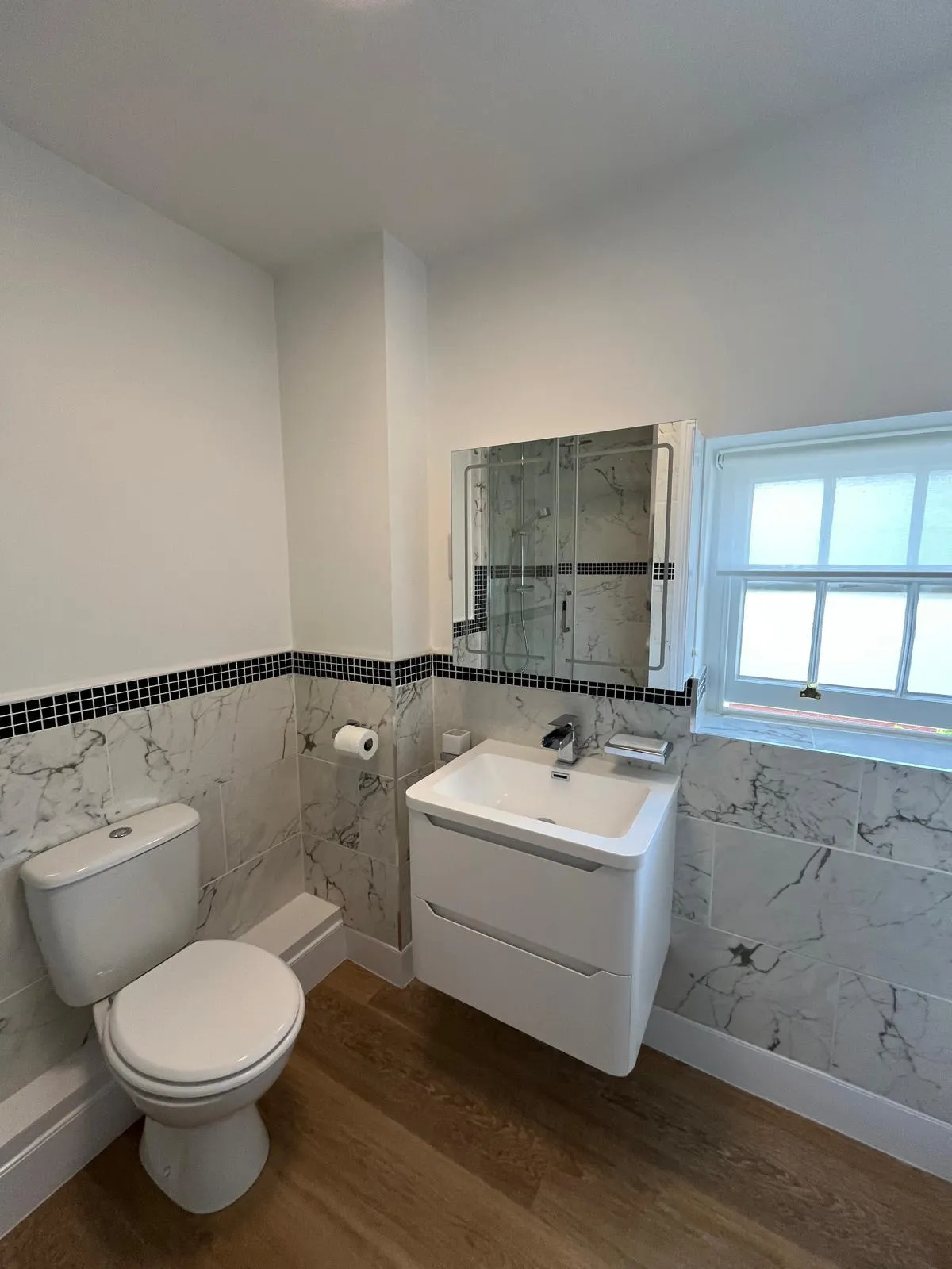 Refurbished bathroom with contrasting grey and white marble tiles