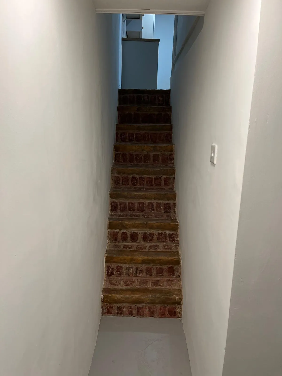 Exposed brick staircase flanked by freshly painted white walls