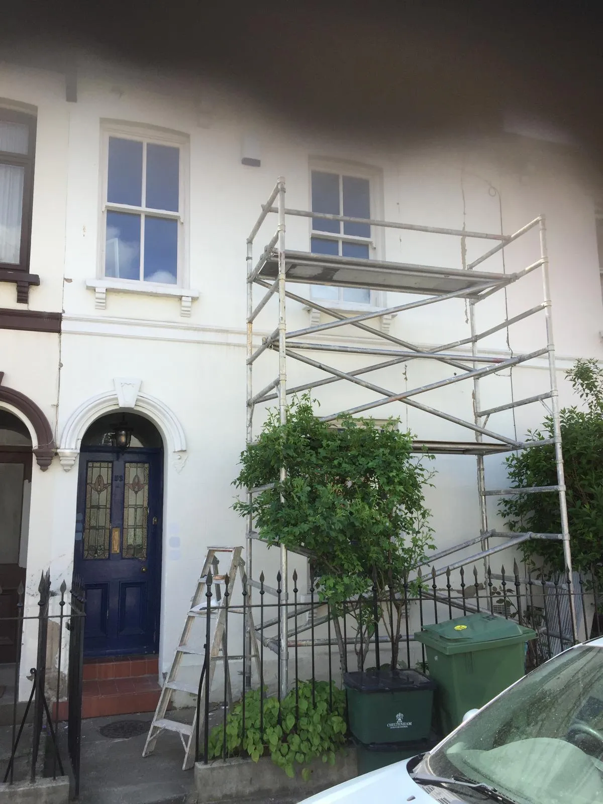 Peeling paint and cracked render on terraced house frontage