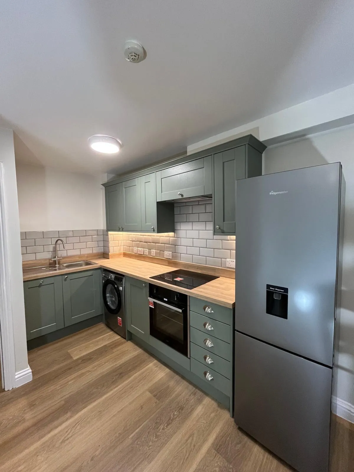 Newly fitted kitchen with sage-green units and wooden worktops