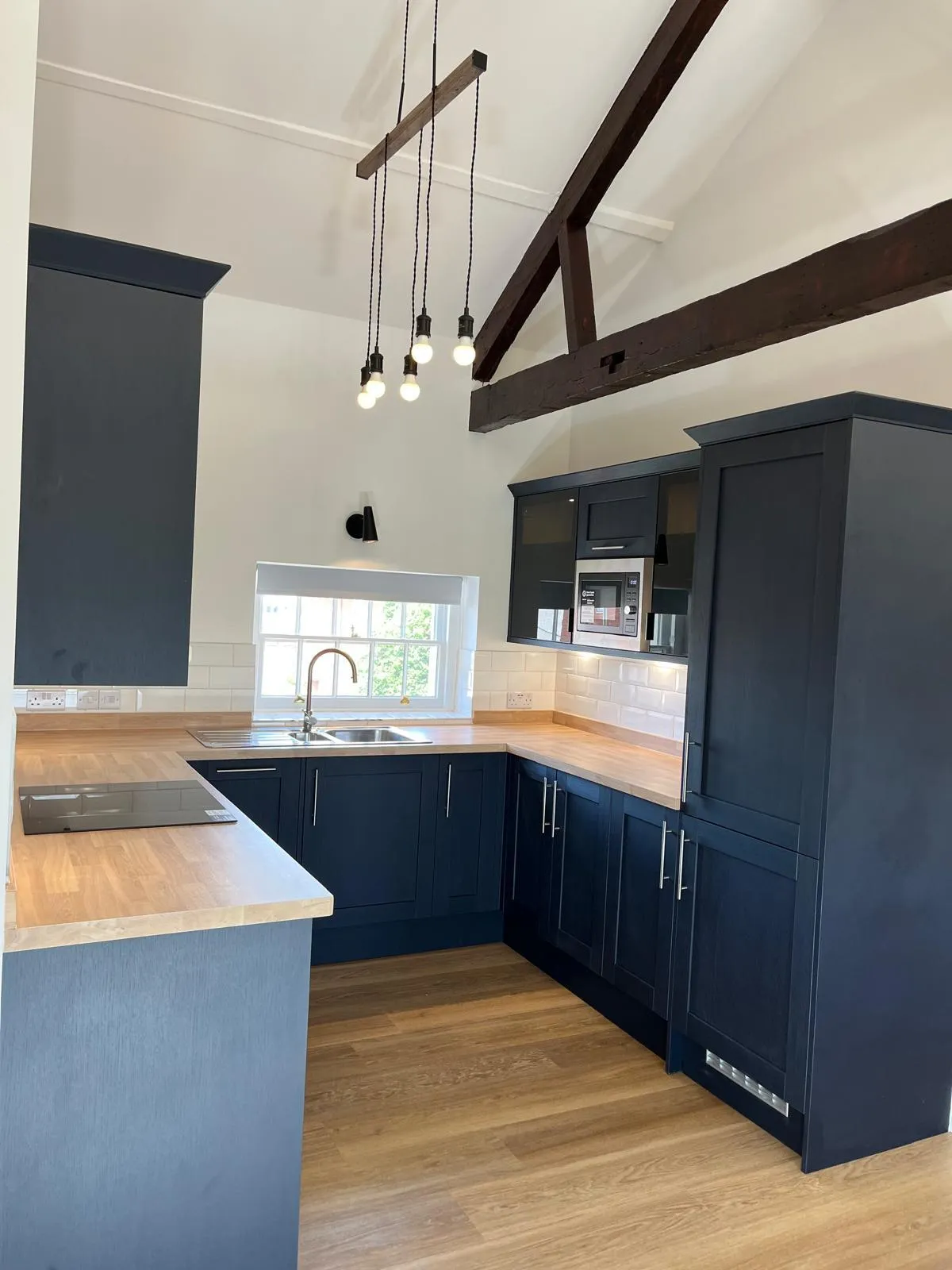 Newly fitted dark shaker kitchen with metro tile splashback and wooden worktop