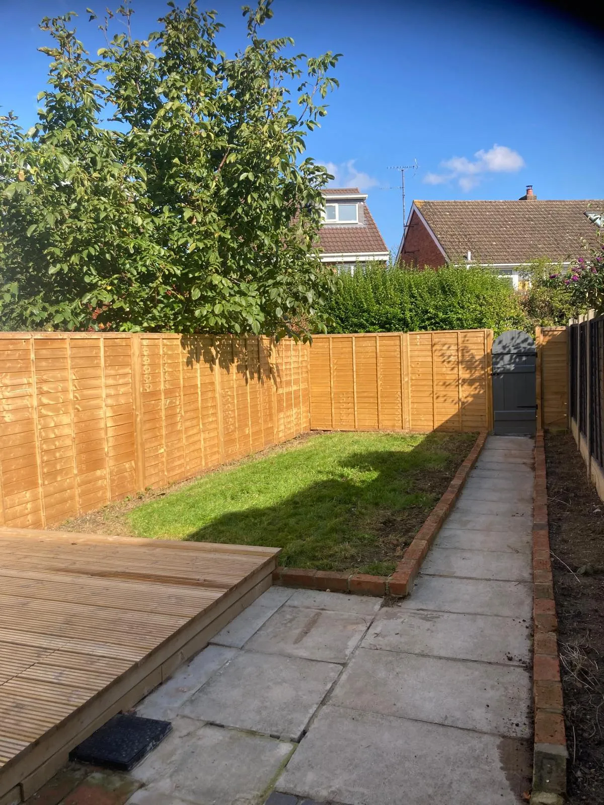 Newly fenced garden with lawn, paving and timber decking area